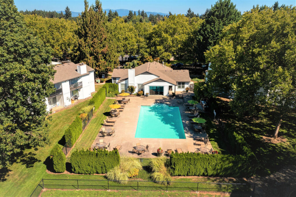 Aerial view of clubhouse with pool, surrounded by large trees