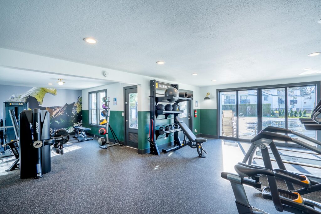 A modern gym with weight machines, a mirrored wall, and medicine balls.