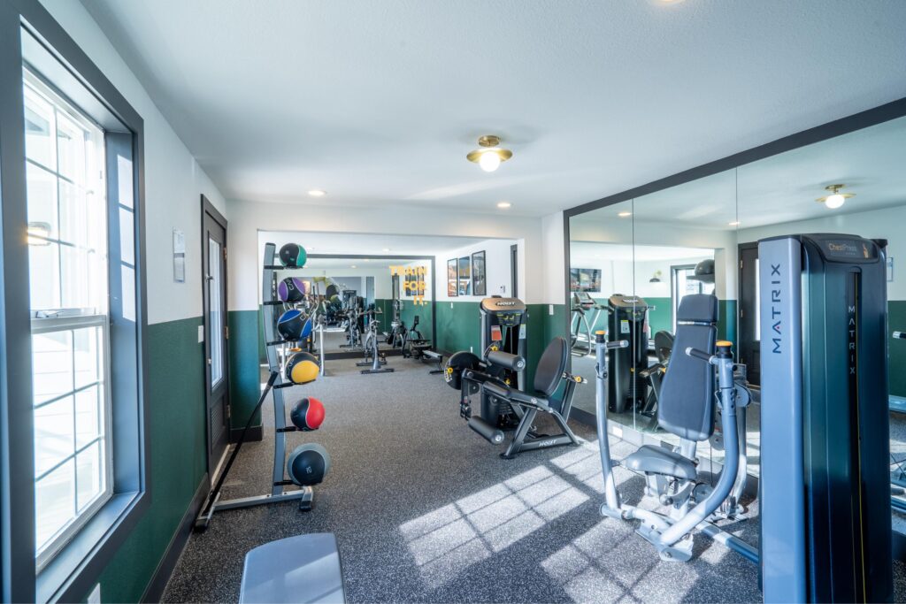 A modern gym with weight machines, a mirrored wall, and medicine balls.
